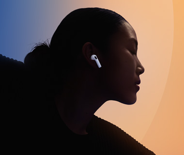 一位扎着头发的人侧脸朝右，耳朵佩戴白色 AirPods 5，背景呈蓝色与暖橙色渐变。